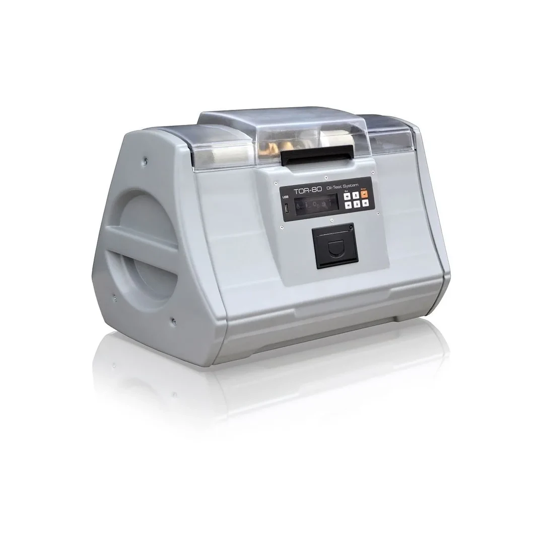 Equipo GlobalCore TOR-80 para medir la tensión de ruptura de aceite de transformador, con carcasa gris y tapa transparente.